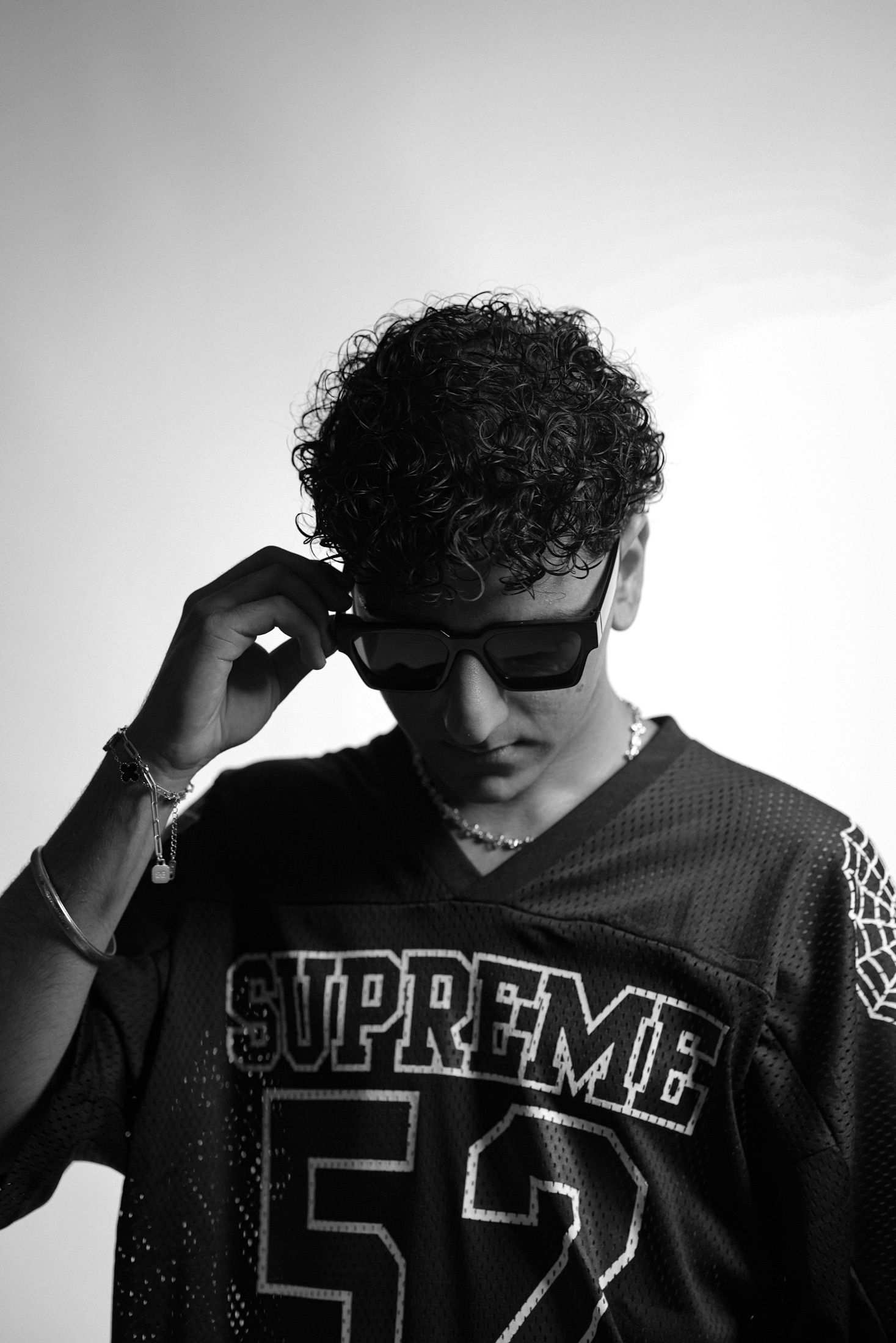 JIANNU adjusting his sunglasses in a Supreme jersey